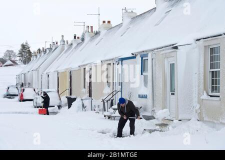 Tempo: Il residente locale Peter Scott libera la neve dal suo percorso fuori della sua casa in Fraser Terrace, Wanlockhead villaggio, Dumfries e Galloway. Foto Stock