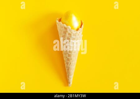 Un cono gelato con un uovo di Pasqua in esso sul luminoso sfondo colorato. Felice concetto di Pasqua. Pasqua sfondo festivo. Vista dall'alto Foto Stock