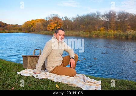 Felice giovane uomo sorridente vicino al lago outdoor in una giornata autunnale Foto Stock