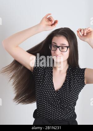 Ritratto di una ragazza Brunette Teen con capelli lunghi con bespectacled ballando con Le Mani in aria Foto Stock