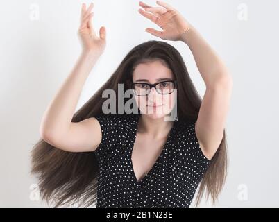 Ritratto di una ragazza Brunette Teen con capelli lunghi con bespectacled ballando con Le Mani in aria Foto Stock