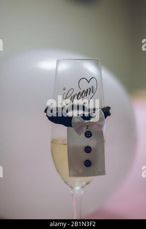 Un bicchiere di champagne di novità con un tuxedo e le parole Sposo sul bicchiere Foto Stock