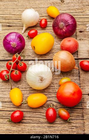 Autunno raccolto verdure cottura sfondo. Assortimento di cipolle e pomodori di diversi tipi. Vecchio sfondo vintage tavole di legno, primo piano Foto Stock