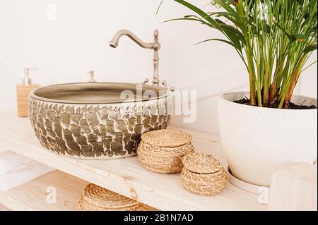 tondo scuro insolito slavello di pietra su un controsoffitto di legno e riutilizzabile organico tessuto da bagno di paglia accessori Foto Stock