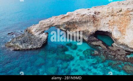 Ponte di pietra per gli amanti Love Bridges sul mare vicino alle montagne sull'isola di Ayia Napa Cipro Foto Stock