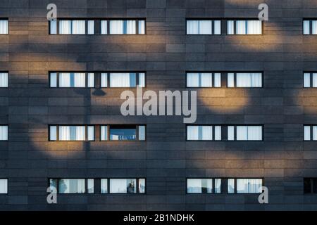 Luce del pomeriggio sulla facciata nera di un edificio urbano con lunghe finestre orizzontali Foto Stock