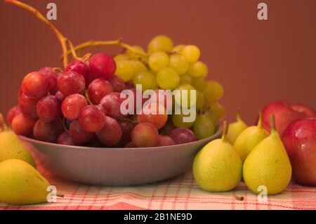 Ancora vita di frutta con uve bianche e nere, pere, mele, con sfondo marrone con spazio per i testi. Foto Stock