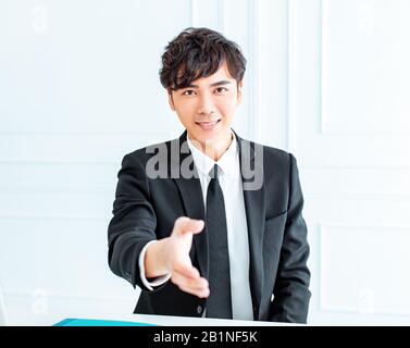 Imprenditore sorridente raggiungere fuori per una stretta di mano Foto Stock