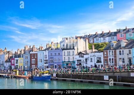 Turisti in banchina presso il Porto Vecchio, passerete davanti ai colorati negozi, ristoranti e proprietà su Trinity Road, Weymouth, Dorset, Inghilterra, Regno Unito Foto Stock