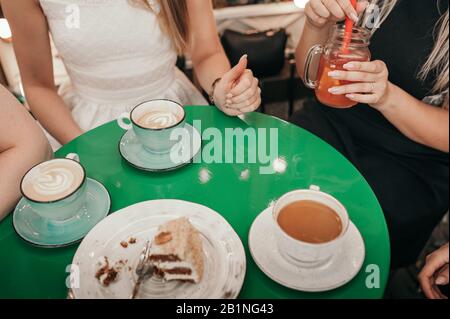 festa di bachelorette in un tavolo rotondo verde nella caffetteria, ragazze senza facce snack caffè, tè e torte Foto Stock
