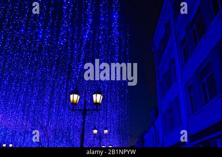 paesaggio notturno della città in luci al neon, una lanterna gialla sullo sfondo di una fantastica decorazione della garland della città in classico colore blu con l'uomo Foto Stock