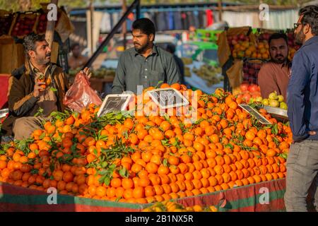 Islamabad, Islamabad Capital Territory, Pakistan - 3 febbraio 2020, UN venditore attende i clienti nel mercato vegetale per vendere frutta arancione. Foto Stock