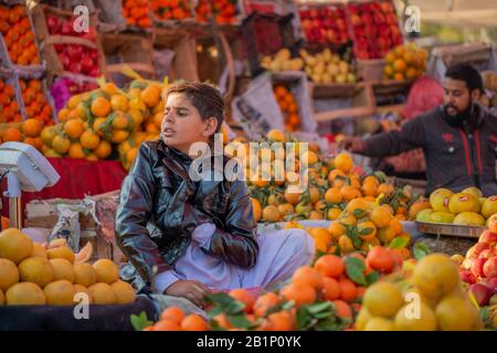 Islamabad, Islamabad Capital Territory, Pakistan - 3 febbraio 2020, UN giovane venditore attende i clienti Nel mercato Della Frutta per vendere i frutti. Foto Stock