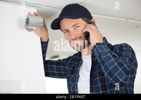 L'uomo installazione di sorveglianza telecamere TVCC a casa Foto Stock