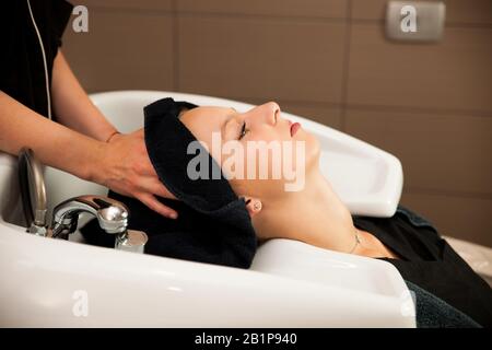 Hair stylist al lavoro - parrucchiere i capelli di lavaggio al cliente prima di fare l'acconciatura Foto Stock