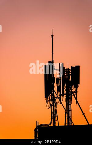 Silhouette di un sito cellulare al tramonto Foto Stock