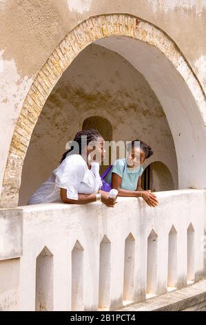 Professore universitario e studenti in visita al Castello di Elmina guardando gli ex quartieri degli schiavi, il Ghana Foto Stock