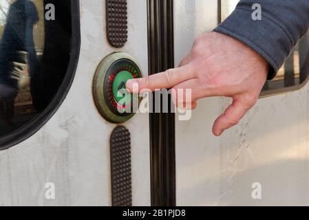 Uomo che preme un pulsante per aprire le porte del treno. Primo piano sparare Foto Stock