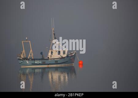 Una barca da pesca ormeggiata in nebbia fitta Foto Stock
