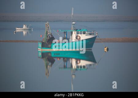barche da pesca all'ancora nella nebbia del mattino sull'estuario Foto Stock