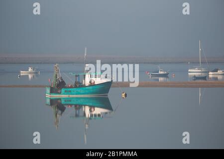 Barche da pesca ad ancora nella nebbia del mattino su un estuario Foto Stock