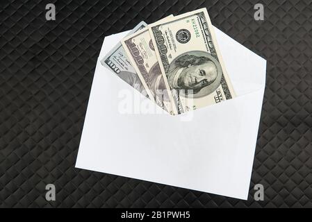 Banconote in dollari USA in busta bianca su sfondo nero. Concetto di tangente, dale, dono, trasferimento di denaro Foto Stock