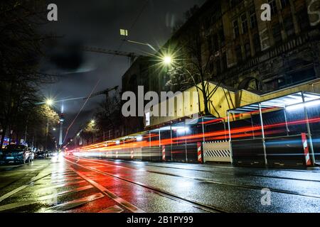 Berlino, Germania. 26th Feb, 2020. Oranienburger Strasse A Berlino-Mitte. Le luci di un tram che passa e le auto passano spiccano come strisce luminose e sono riflesse dalla strada bagnata. Sullo sfondo è possibile vedere la torre della televisione. Effetto di pulizia a causa di un tempo di esposizione più lungo. Credito: Gerald Matzka/dpa-Zentralbild/ZB/dpa/Alamy Live News Foto Stock