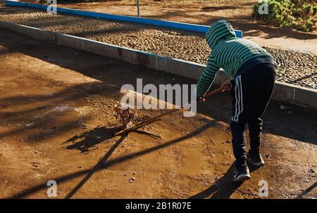 Essaouira, MAROCCO - 17 GENNAIO 2020: Il ragazzo marocchino non identificato spazza via terra. Le persone soffrono di povertà a causa della cattiva economia. Foto Stock