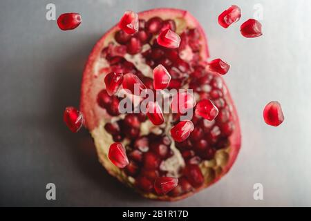 Dolce saporito agrodolce semi di melograno che volano sopra la frutta pelata, vista dall'alto, fuoco selettivo Foto Stock