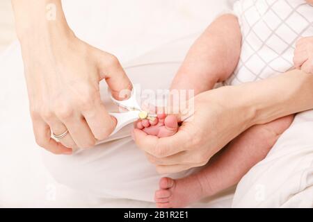 Madre usa speciali forbici per unghie del bambino per tagliare unghie del neonato Foto Stock