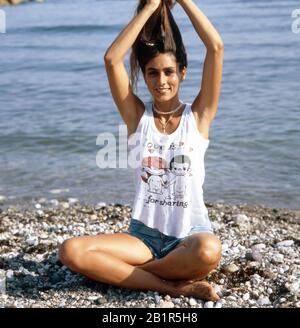 Homerory der italienisch amerikanischen Sängerin und Schauspielerin Romina Power im Schneidersitz am Strand, Italien mitte 1980er Jahre. Home storia della cantante e attrice italo-americana Romina Power seduto a gambe incrociate sulla spiaggia, Italia a metà 1980s. Foto Stock