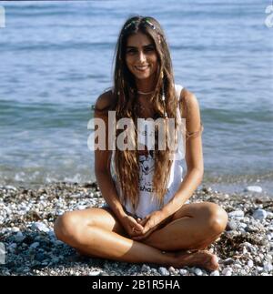 Homerory der italienisch amerikanischen Sängerin und Schauspielerin Romina Power im Schneidersitz am Strand, Italien mitte 1980er Jahre. Home storia della cantante e attrice italo-americana Romina Power seduto a gambe incrociate sulla spiaggia, Italia a metà 1980s. Foto Stock