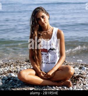 Homerory der italienisch amerikanischen Sängerin und Schauspielerin Romina Power im Schneidersitz am Strand, Italien mitte 1980er Jahre. Home storia della cantante e attrice italo-americana Romina Power seduto a gambe incrociate sulla spiaggia, Italia a metà 1980s. Foto Stock