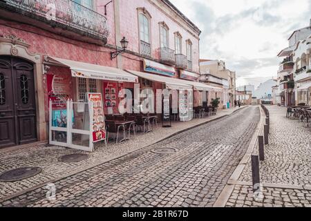 Silves, Portogallo - 23 gennaio 2020: Belle strade acciottolate con piastrelle rosa sugli edifici nel piccolo villaggio in Algarve Foto Stock