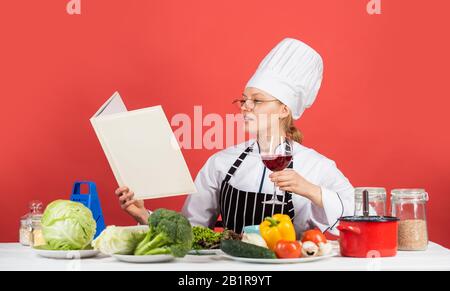 pratica di più. chef professionista leggere la ricetta per cucinare. chef femminile preparare il piatto. cucinare nella sua cucina. Apri il ricettario per una cucina sana. Mantiene un segreto sugli ingredienti. Donna utilizza Cookbook. Foto Stock