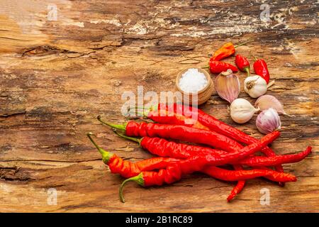 Peperone rosso e arancio con fondo di cottura all'aglio. Ingredienti tradizionali per la preparazione di pasti sani. Corteccia di legno sfondo, mare sal Foto Stock