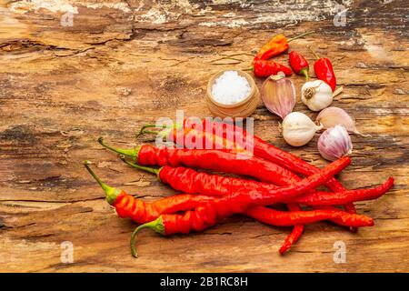 Peperone rosso e arancio con fondo di cottura all'aglio. Ingredienti tradizionali per la preparazione di pasti sani. Corteccia di legno sfondo, mare sal Foto Stock