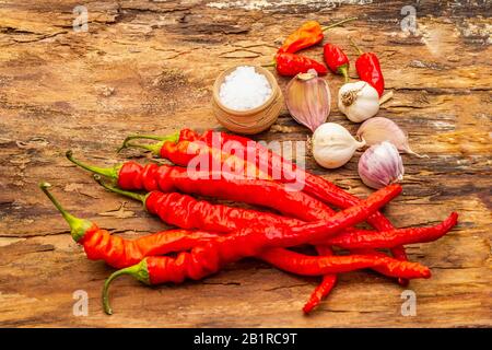 Peperone rosso e arancio con fondo di cottura all'aglio. Ingredienti tradizionali per la preparazione di pasti sani. Corteccia di legno sfondo, mare sal Foto Stock