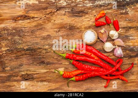 Peperone rosso e arancio con fondo di cottura all'aglio. Ingredienti tradizionali per la preparazione di pasti sani. Corteccia di legno sfondo, mare sal Foto Stock