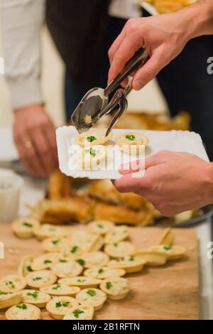 Uomo che si serve con tartine vegetariane all'evento di celebrazione. Foto Stock