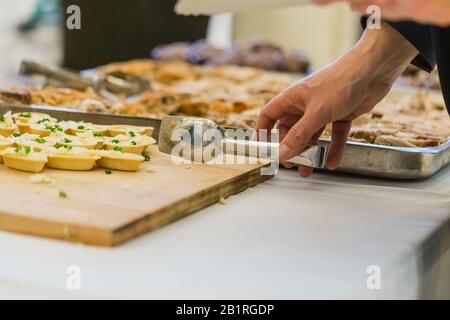 Primo piano dell'uomo che tiene il tong dell'arnese sul tavolo a buffet con tartine all'evento. Foto Stock