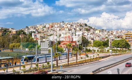 Vista panoramica del Pireo vicino Atene, Grecia. Soleggiato paesaggio urbano del Pireo con tram e strada. Scenario di una città su una collina in estate. Foto Stock