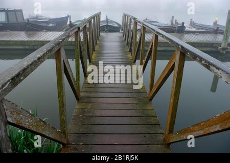 Passerella in legno in una giornata nebbiosa nel porto di Catarroja Valencia Spagna. Foto Stock