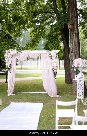 Arco per matrimoni e sedie in giardino. Foto Stock