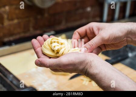 Gli chef tengono un mazzetto di pasta fresca fatta con tagliatelle Foto Stock