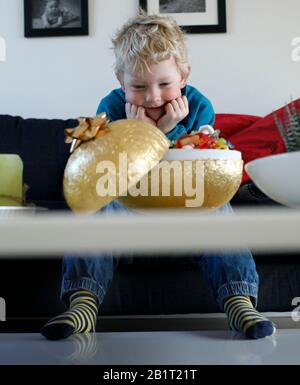 Un piccolo ragazzo guarda un uovo di Pasqua dorato riempito di caramelle in peso sciolto. Foto Jeppe Gustafsson Foto Stock