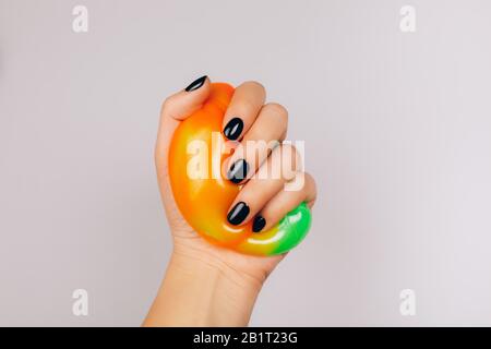 mani con manicure nero che tiene la calce in arancione e verde vibrante colori Foto Stock
