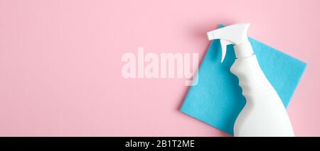 Flacone spray per pulizia su tovagliolo blu su sfondo rosa. Disposizione piatta, vista dall'alto. Servizi di pulizia. Foto Stock