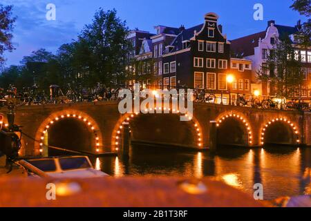 Amsterdam in den Niederlanden, beleuchtete Bruecke bei Nacht, Grachten, Foto Stock