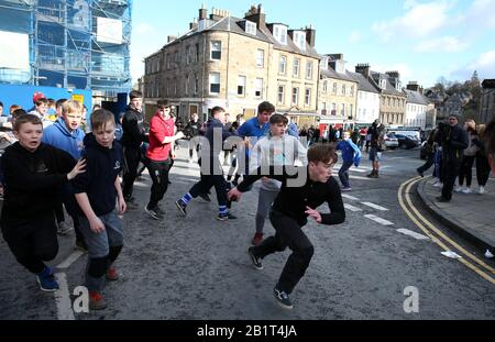 I ragazzi si sfidano per la palla di pelle durante l'evento di gioco annuale di Jedburgh Ba' su High Street di Jedburgh nei confini scozzesi. Data dell'immagine: Giovedì 27 febbraio 2020. L'evento annuale è iniziato nel 1700 e il primo gioco in assoluto è stato presumibilmente giocato con la testa di un inglese. Coinvolge due squadre, gli Uppies (residenti dalla parte superiore di Jedburgh) e i Doonies (residenti dalla parte inferiore di Jedburgh) che ottengono la palla o alla parte superiore o inferiore della città. La palla, realizzata in pelle, imbottita di paglia e decorata con nastri che rappresentano i capelli, viene gettata nella Foto Stock